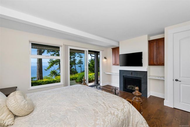 Bedroom featuring a tiled fireplace, dark wood-style flooring, and access to outside | Image 60