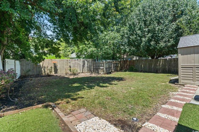 Fenced backyard featuring a storage unit | Image 31