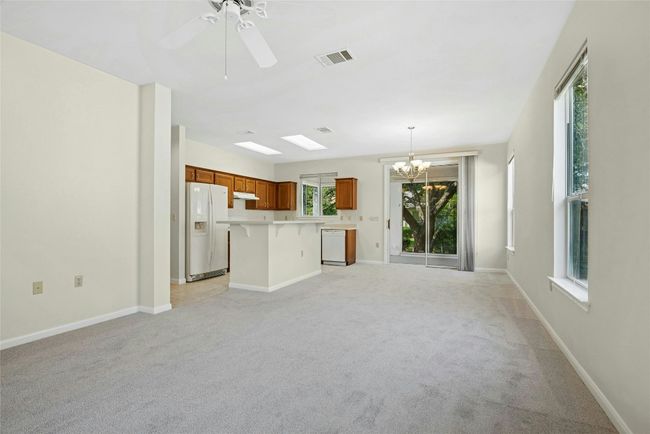 Unfurnished living room featuring a chandelier, light carpet, ceiling fan, and baseboards | Image 7