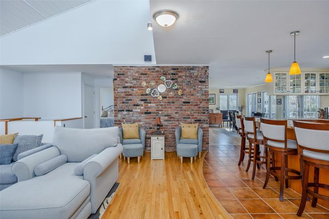 Living area featuring vaulted ceiling, wood finished floors, and brick wall | Image 10