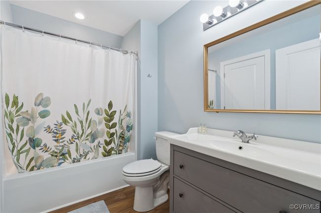 Full bath featuring shower / bathtub combination with curtain, toilet, wood finished floors, and vanity | Image 39
