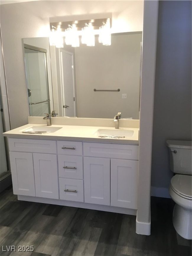 Bathroom featuring toilet, double vanity, a sink, and wood finished floors | Image 25