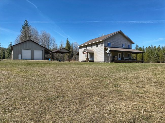 View of yard featuring an outbuilding, a porch, and a garage | Image 49