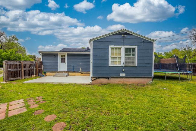 Back of house featuring a trampoline, a patio area, fence, and a yard | Image 24