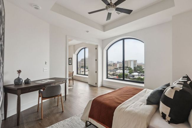 Bedroom with a tray ceiling, a city view, wood finished floors, and baseboards | Image 17