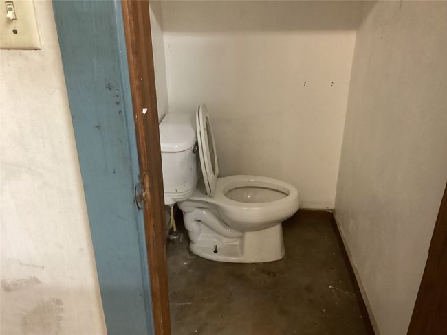 Bathroom featuring shop area toilet and unfinished concrete floors | Image 11