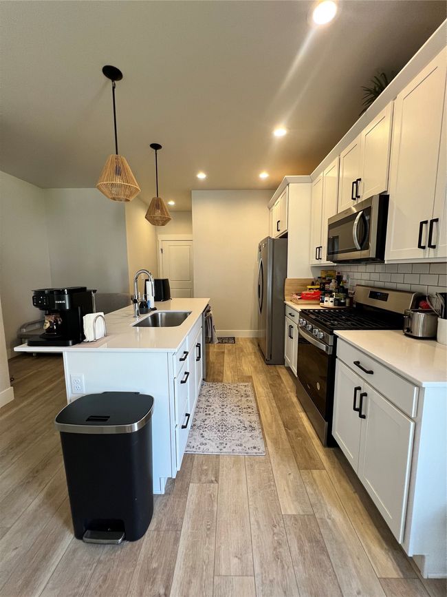 Kitchen with a sink, range, refrigerator, a kitchen island with sink, and white cabinets | Image 11