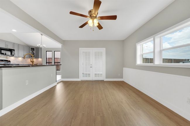 Unfurnished living room with light wood-style flooring, healthy amount of natural light, a ceiling fan, a chandelier, and vaulted ceiling | Image 11