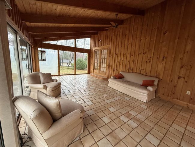 Living room featuring wood ceiling, wooden walls, ceiling fan, and light tile patterned floors | Image 17