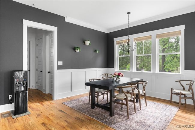 Dining space with a chandelier, light wood finished floors, a decorative wall, wainscoting, and crown molding | Image 14