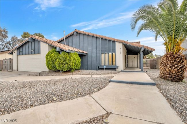 Mid-century home with board and batten siding, fence, a garage, a tile roof, and concrete driveway | Image 26