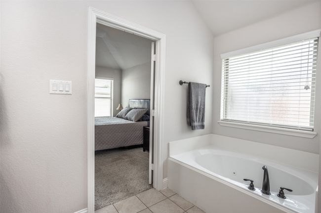 Bathroom with a whirlpool tub, tile patterned floors, connected bathroom, and vaulted ceiling | Image 29