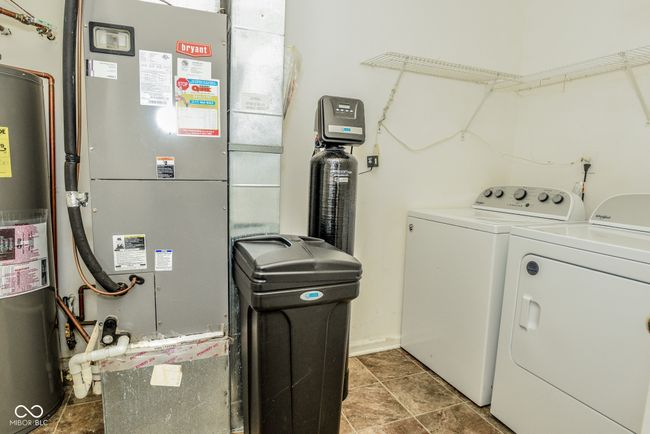 laundry area featuring washer and clothes dryer, heating unit, and water heater | Image 9