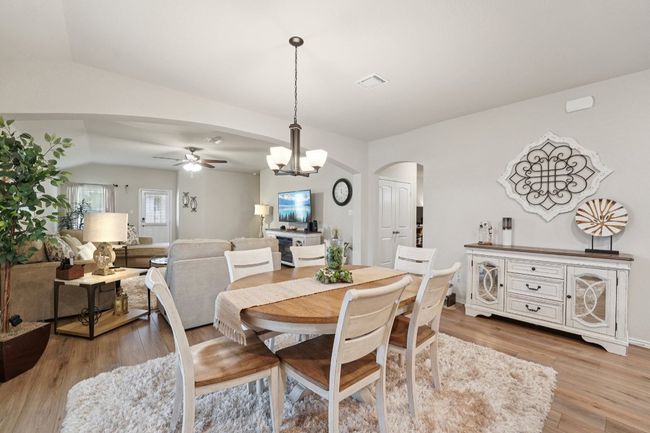 Dining space with arched walkways, lofted ceiling, a ceiling fan, light wood-type flooring, and a chandelier | Image 9