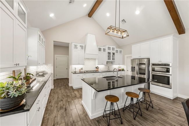 Kitchen featuring appliances with stainless steel finishes, a sink, beamed ceiling, a kitchen breakfast bar, and dark wood-style flooring | Image 8