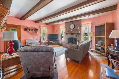 Living room featuring hardwood / wood-style floors, beamed ceiling, brick wall, and a brick fireplace | Image 3