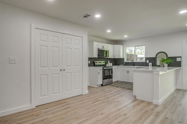 Kitchen with appliances with stainless steel finishes, light wood finished floors, a peninsula, decorative backsplash, and recessed lighting | Image 9