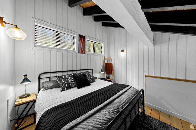Bedroom featuring wood finished floors, wood walls, and beamed ceiling | Image 15