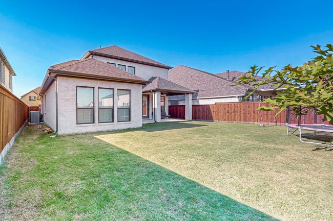 Back of property with a trampoline, a shingled roof, and brick siding | Image 39