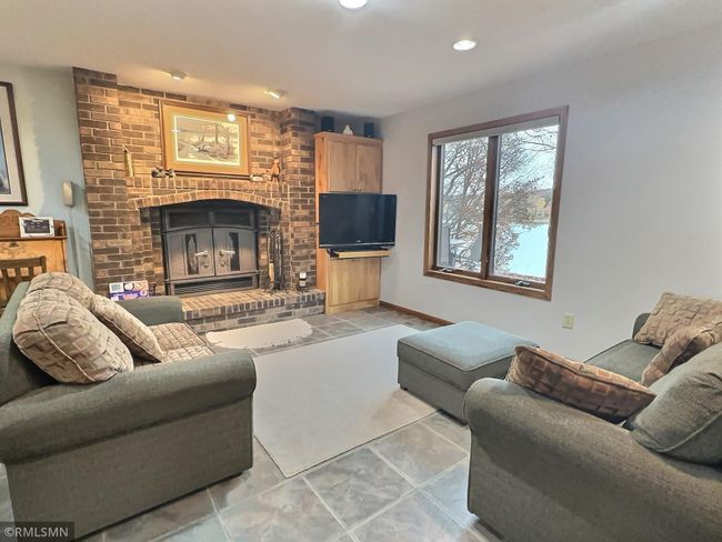 The lower level is the heart of the home. Ceramic tile throughout this open gathering space. You will love cozying up to this wood burning fireplace during the cooler months. | Image 25