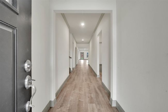 Corridor with light wood-type flooring, crown molding, baseboards, and recessed lighting | Image 4