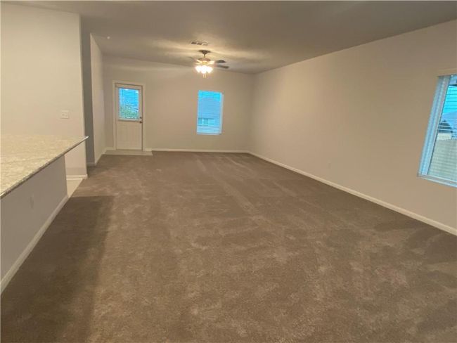 Unfurnished room featuring dark carpet, a ceiling fan, and baseboards | Image 4