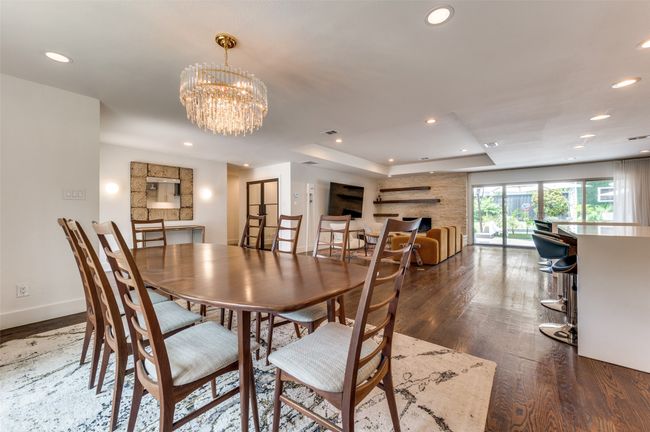 Dining room with wood finished floors, a tray ceiling, recessed lighting, baseboards, and a chandelier | Image 15