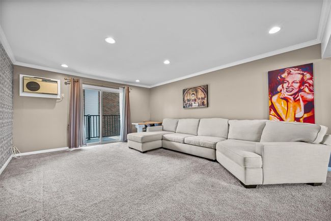 Carpeted living area featuring crown molding, recessed lighting, and a wall unit AC | Image 6