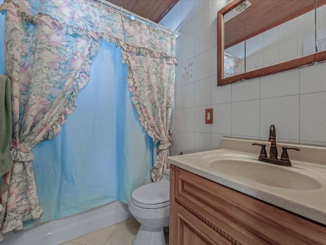 Bathroom featuring vanity, tile patterned flooring, a shower with curtain, and tile walls | Image 15
