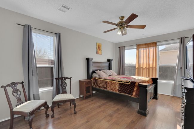 Bedroom with a textured ceiling, visible vents, and dark wood-style flooring | Image 16