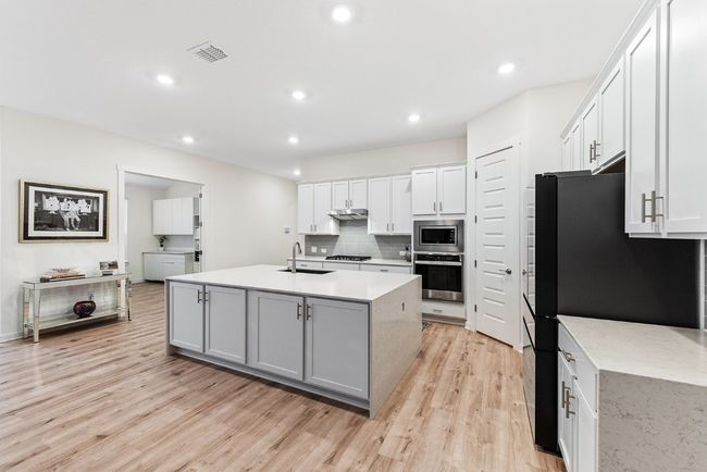 Kitchen with visible vents, a sink, light countertops, under cabinet range hood, and appliances with stainless steel finishes | Image 11