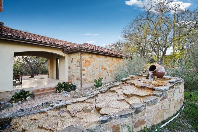View of side of home with a patio area, stone siding, and a tile roof | Image 36