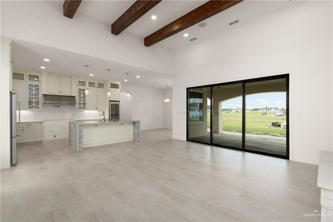 Chef-inspired kitchen showcasing custom cabinetry with glass-front upper accents, elegant pendant lighting, and a dramatic waterfall-edge granite island. | Image 7