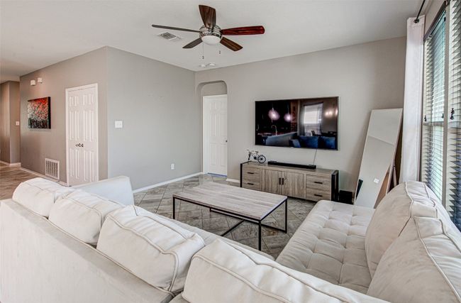 Living room with arched walkways, visible vents, baseboards, and ceiling fan | Image 7