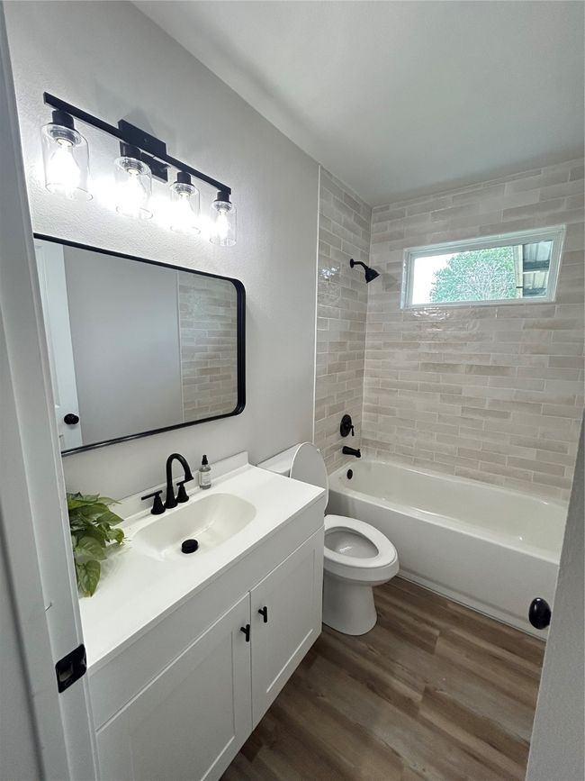 Bathroom featuring wood finished floors, vanity, toilet, and washtub / shower combination | Image 10