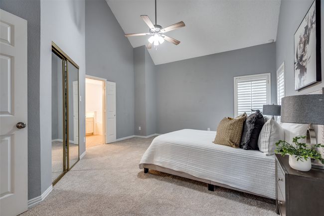 Bedroom with high vaulted ceiling, light colored carpet, baseboards, ensuite bathroom, and ceiling fan | Image 13
