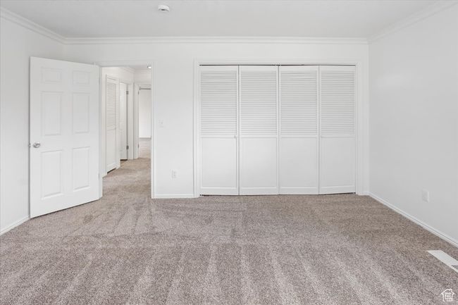 Unfurnished bedroom with a closet, carpet flooring, visible vents, baseboards, and ornamental molding | Image 22