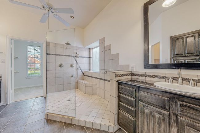 Bathroom featuring a walk in shower, vanity, ceiling fan, and vaulted ceiling | Image 23