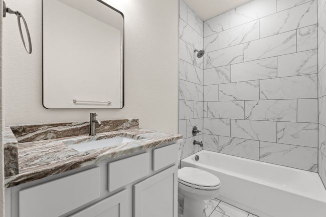 Bathroom with toilet, vanity, marble look tile flooring, and tub / shower combination | Image 28