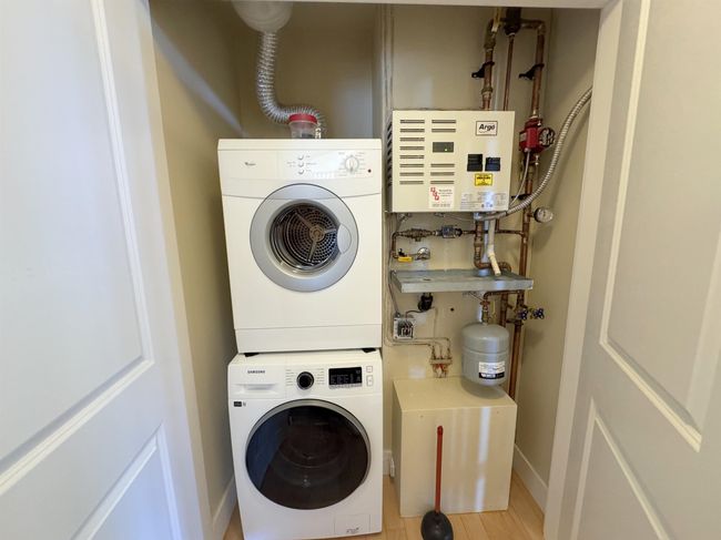 Washroom with stacked washer / dryer, water heater, and wood finished floors | Image 30