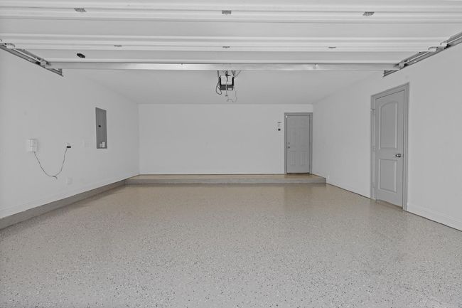 Garage with a garage door opener, electric panel, and baseboards | Image 22