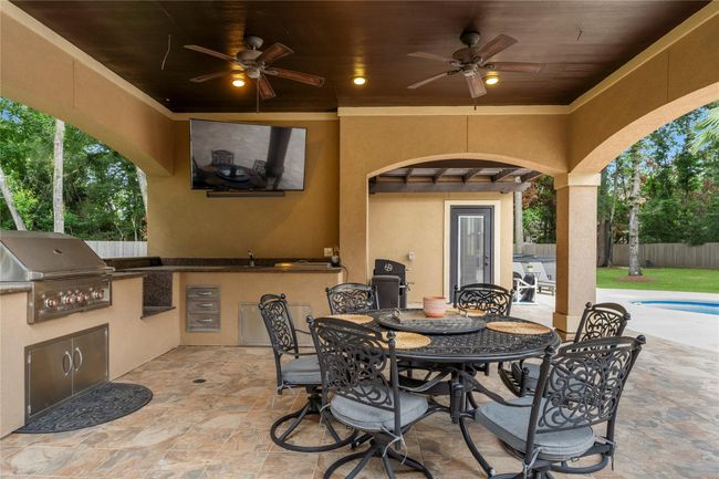 The outdoor kitchen is fully equipped with a professional-grade grill, built-in sink, and integrated TV connections—seamlessly blending culinary functionality with modern convenience. - Keep browsing to see what's behind that door! | Image 6