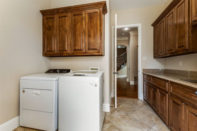 The spacious Utility Room includes built in cabinetry, granite countertops, a sink, and a bonus room (not shown) to the left of the washer/dryer. | Image 29