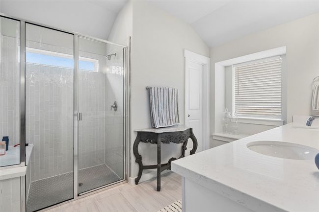 Bathroom featuring double vanity, a shower stall, and vaulted ceiling | Image 21