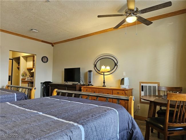 Bedroom with dark wood-type flooring, ornamental molding, a textured ceiling, and a ceiling fan | Image 14