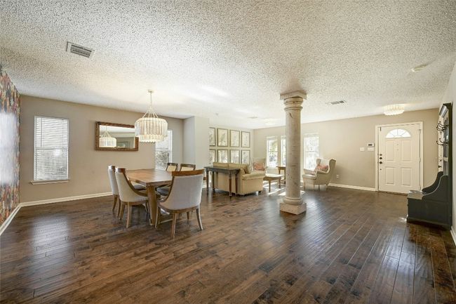 Dining area featuring decorative columns, dark wood-style flooring, healthy amount of natural light, a textured ceiling, and a chandelier | Image 6