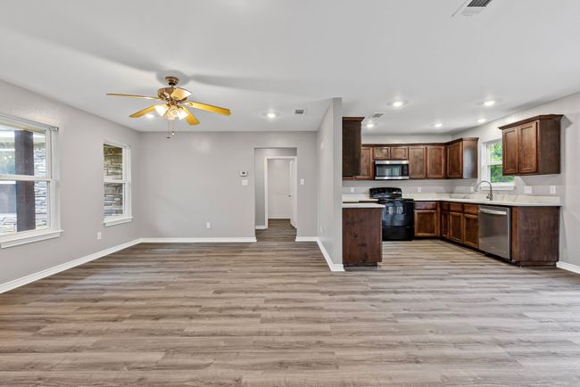 Kitchen with appliances with stainless steel finishes, open floor plan, light countertops, light wood-type flooring, and a ceiling fan | Image 24