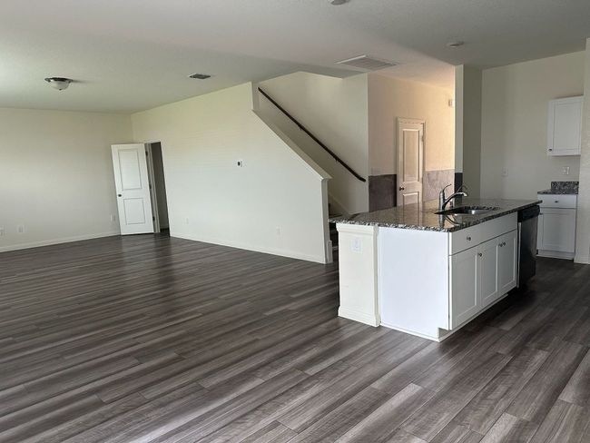 Kitchen featuring open floor plan, dark stone countertops, dark wood-type flooring, and white cabinetry | Image 23