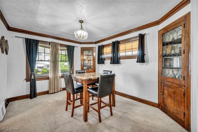 Carpeted dining room featuring a textured ceiling, crown molding, and a chandelier | Image 10