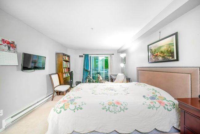Bedroom featuring a baseboard radiator, access to exterior, and light colored carpet | Image 26